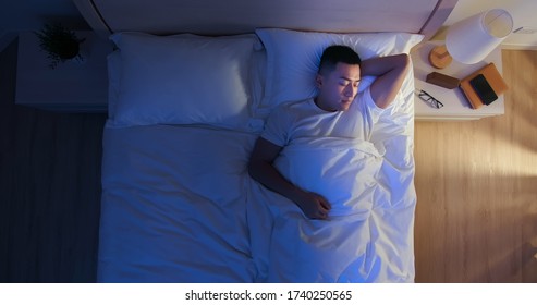 top view of asian man sleep well with smile at night 