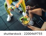 Top view Asian man and woman healthy eating salad after exercise at fitness gym. Two athlete eating salad for health together. Selective focus on salad bowl on hand.