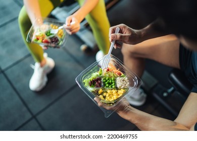 Top view Asian man and woman healthy eating salad after exercise at fitness gym. Two athlete eating salad for health together. Selective focus on salad bowl on hand. - Shutterstock ID 2200469755