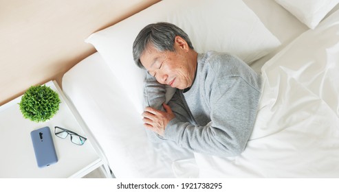 top view of asian senior man lying on bed sleep well with smile in bedroom at home