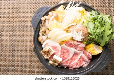 Top View Of Asian Style Hot Pot With Corn Beef, A Lot Of Vegetables, And Mushroom On A Brown Mat.