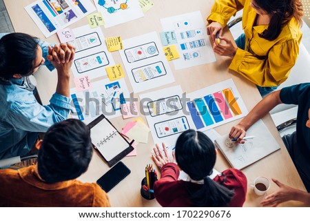 top view asian ux developer and ui designer brainstorming about mobile app interface wireframe design on table with customer brief and color code at modern office.Creative digital development agency