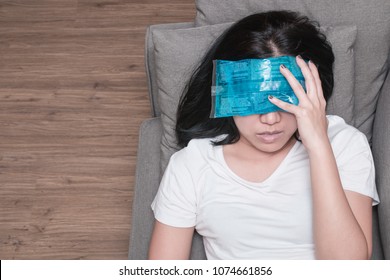 Top view of Asian woman with cold pack on her forehead for relief fever headaches and migraines