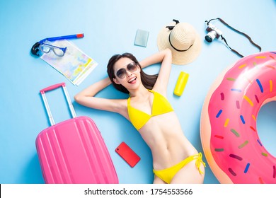 Top view of asian woman is ready to travel wearing bikini swimsuit with luggage and suitcase