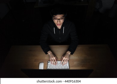 Top View Of Asian Young Man Sitting And Using Laptop In Dark Room