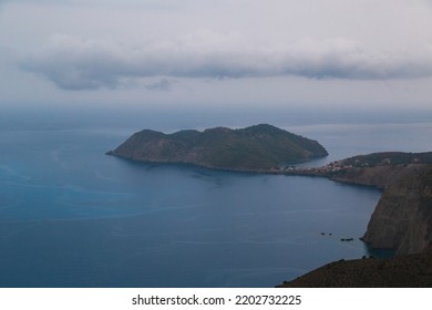 Top view at Asos village and Assos peninsula during bad weather conditions, thunderstorm and rain, with low dark clouds and visible currents at sea. Cephalonia, Greece