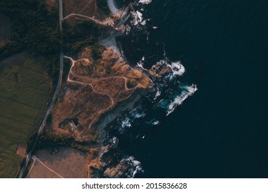 Top View Of An Asphallt Road Located Near The Sea. High Angle Of Road Surrounded By Many Dirt Paths. 