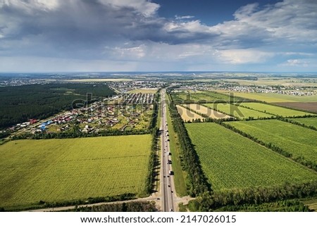 Top view of the asphalt road in the middle of agricultural fields on a bright sunny day against the sky. Aerial photo of landscape