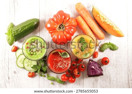 Top view of assorted fresh cold vegetable soups and raw ingredients on white wooden table