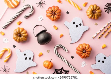 Top view of assorted Halloween decorations and candies including pumpkins, ghost shapes, candy canes on a pink background - Powered by Shutterstock