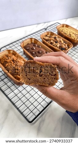 Top view of assorted homemade mini loaf cakes placed in paper baking molds and cooling on a metal wire rack over a white background.