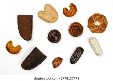 Top view of assorted pastries, bread, croissants, rolls, and chocolate desserts arranged on a white background with copy space