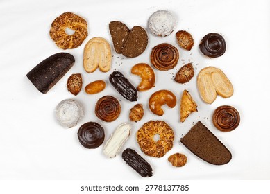Top view of assorted pastries, bread, croissants, rolls, and chocolate desserts arranged on a white background with copy space