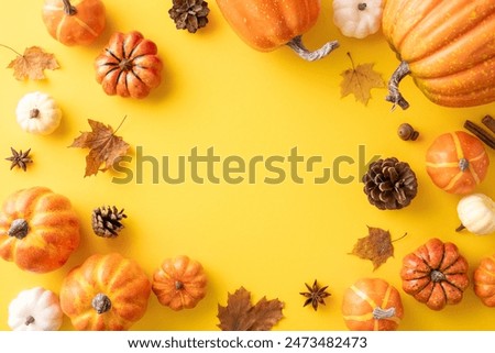 Top view of assorted pumpkins and fall leaves arranged in a circle on a yellow background. Perfect for autumn and Thanksgiving themes