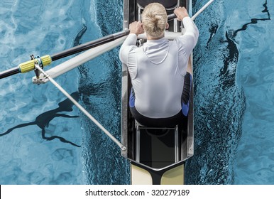 Top View Of Athletic Competition Rower, Who Strokes His  Paddle Through Metallic Blue Water.