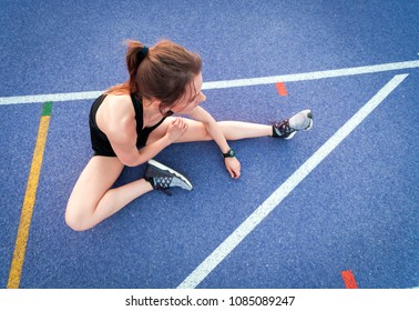 Top view of athletic woman sitting on running track and resting after training - Powered by Shutterstock