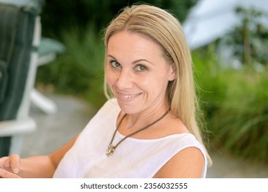 Top view of an attractive woman in her forties looking up from below with a real psycho grin while sitting on the terrace - Shutterstock ID 2356032555