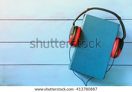 top view of audio book concept, blue book cover and headphones over wooden table