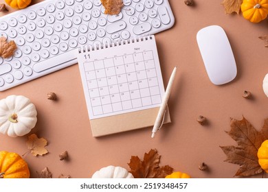 Top view of an autumn themed office desk with a calendar, keyboard, mouse, pumpkins, and leaves, creating a cozy workspace atmosphere - Powered by Shutterstock