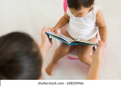 Top view of baby reading book on potty