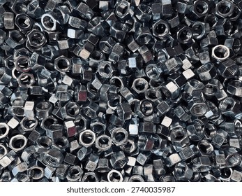 Top view background of a large group of silver metallic hex nuts. This industrial hardware texture features shiny steel fasteners, perfect for themes related to construction, mechanical engineering, automotive repair, manufacturing tools, and DIY home improvement supplies.
