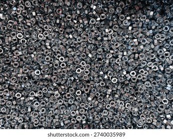 Top view background of a large group of silver metallic hex nuts. This industrial hardware texture features shiny steel fasteners, perfect for themes related to construction, mechanical engineering, automotive repair, manufacturing tools, and DIY home improvement supplies.
