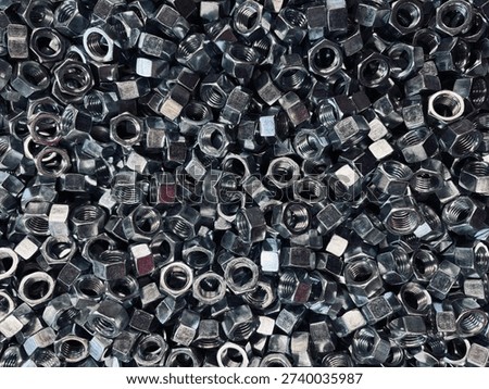 Top view background of a large group of silver metallic hex nuts. This industrial hardware texture features shiny steel fasteners, perfect for themes related to construction, mechanical engineering, automotive repair, manufacturing tools, and DIY home improvement supplies.
