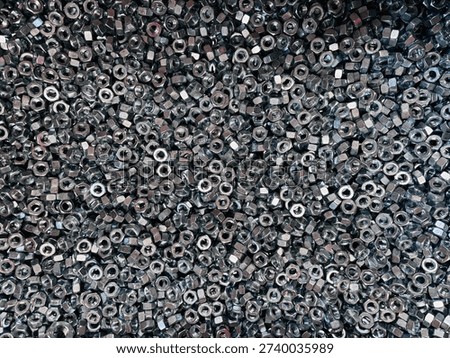 Top view background of a large group of silver metallic hex nuts. This industrial hardware texture features shiny steel fasteners, perfect for themes related to construction, mechanical engineering, automotive repair, manufacturing tools, and DIY home improvement supplies.
