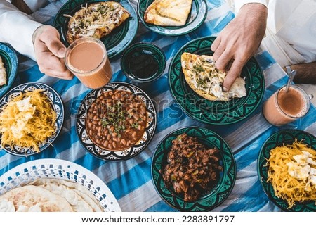 top view of Bahraini dining table in Ramadan with Ramadan decoration, that contains Karak, samosa, Loba, Lgemat, Balalet, Eggs, and other Arab food for Breakfast and Dinner