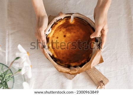 Top view of baker holding basque cheesecake in baking paper. Sugar free food