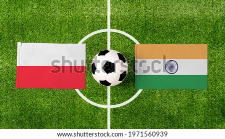 Top view ball with Poland vs. India flags match on green football field.