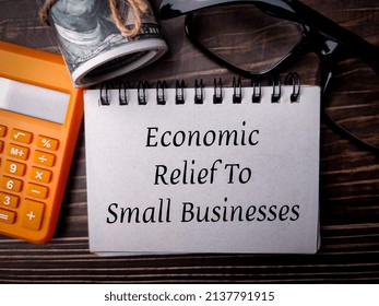 Top View Banknotes,glasses,and Calculator With Text Economic Relief To Small Businesses On Wooden Background.