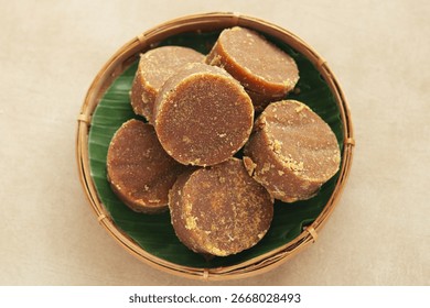 Top view of a basket filled with solid, dark brown palm sugar discs (gula jawa or gula merah), a traditional sweetener used in a variety of desserts, beverages, and savory dishes.