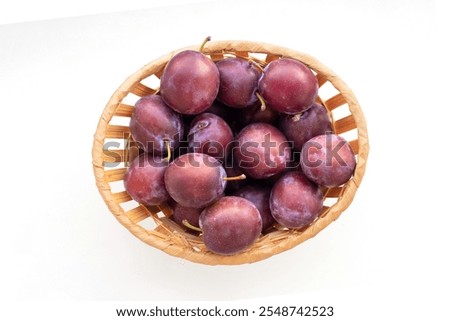 Top view of basket with plums isolated on white.
