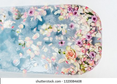 Top View Of Bath Filled With Blue Bubble Water, Flowers And Petals, Spa Or Selfcare Concept