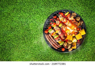 Top view of bbq grill, grilled meat, vegetables, mushrooms with flames and smoke. Placed on green grass lawn. Grilled food, copy space. - Powered by Shutterstock