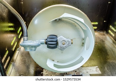 Top View Of BBQ Propane Tank And Regulator Inside A Barbecue