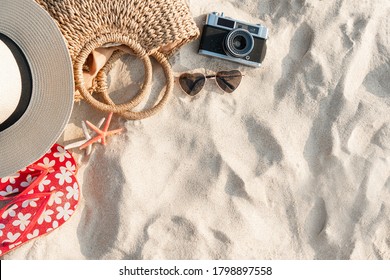 Top View Of Beach Accessories. Straw Hat, Bag, Sunglasses, Coral, Flip Flops And Camera On Sand At Tropical Beach. Summer Holiday Concept. Flat Lay With Copy Space