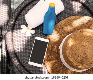 Top view of beach accessories. Sunscreen, straw hat, towel and smartphone on the desk at poolside. Copy space, flat lay - Powered by Shutterstock