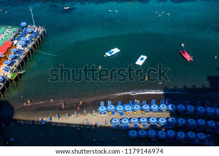 Top view of beach and blue umbreallas and sea in Italy Sorrento beautiful beach and water. boats and tourist swimming and enjying the vacation near Naples in italy. Relaxing in holiday summer