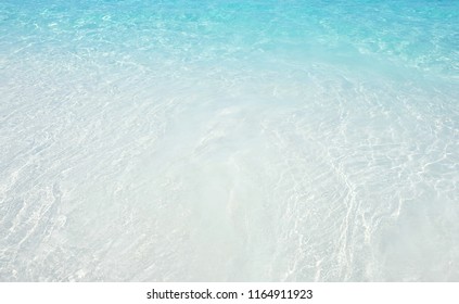 Top view of beautiful crystal clear sea water at tropical beach. White powder sand is so bright when reflected by sun at noon. See through the surface of  bright turquoise water.