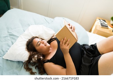 Top View Of A Beautiful Obese Woman Lying And Resting In A Comfortable Bed While Reading A Book