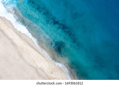 Top view of beautiful white sand beach with turquoise ocean water, aerial drone shot