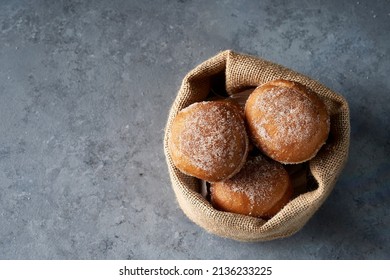 Top view Berliners in a burlap basket on gray base. The berliners are also known as berlin balls, bollo, bolinha or bolas de fraile