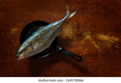 Top View Of A Big Tuna Fish Oversizing A Small Frying Pan, A View Conveying The Concept Of Contrast, Greediness, Being Overambitious, Failure To Be Objective, Trying To Seize The Unseizable.