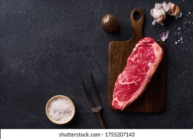 Top View Black Angus Prime Beef Striploin Steak On Cutting Board Concrete Background Copy Space. Flat Lay Cooking Ingredient