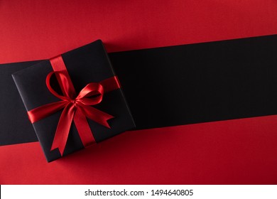 Top View Of Black Christmas Boxes With Red Ribbon On Black Background With Copy Space For Text. Black Friday And Boxing Day Composition.