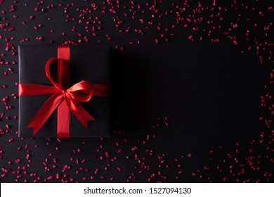 Top view of black christmas boxes with red ribbon on black background with copy space for text. black Friday composition.