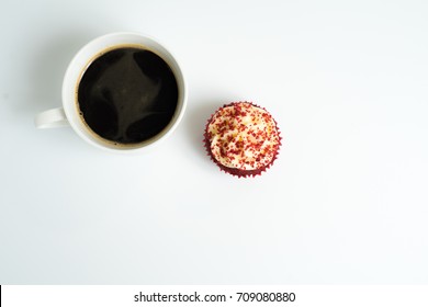 Top View Of Black Coffee Cup With A Red Velvet Cupcake On Top Left Corner In White Background