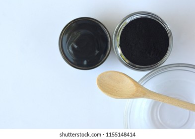 Top View Of Black Cosmetic Activated Charcoal Powder And Beauty Face Mask 
Mixture On White. Oily Skin, Detox And Acne Treatment.
